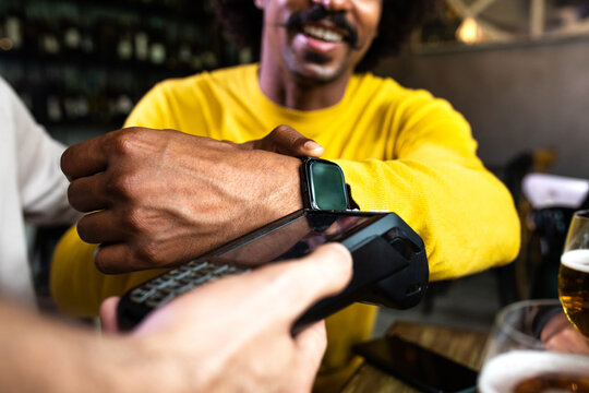 Close Up Of African American Man Paying Bill With Wrist Watch In A Restaurant.