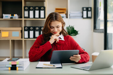 Obraz premium Asian business woman typing laptop and tablet Placed at the table at the office.