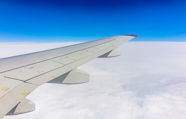 View from the airplane window at a beautiful cloudy sky and the airplane wing