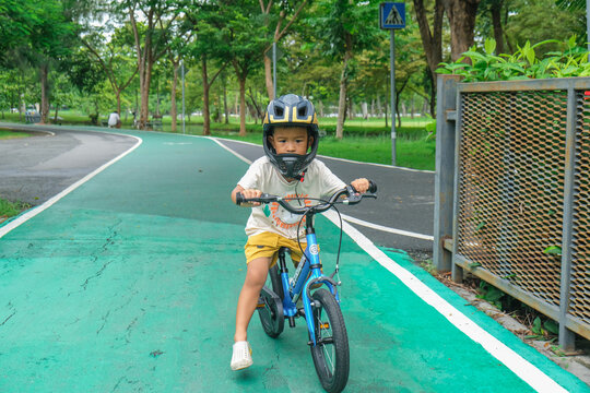 Little asian bpy enjoying ride bicycle in city public park
