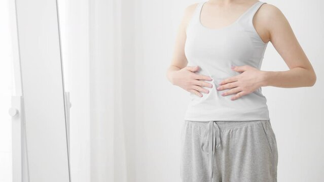 鏡でウェストをチェックする若い女性　ダイエットイメージ