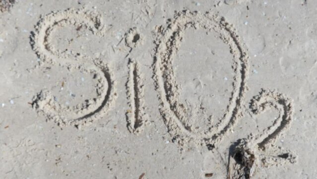 SiO2 Silicon Dioxide Silica written on beach in sand
with finger Handheld Pan Zoom In Out