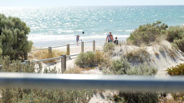 Father and Son walk along sand path toward Beach Grange Beach South Australia