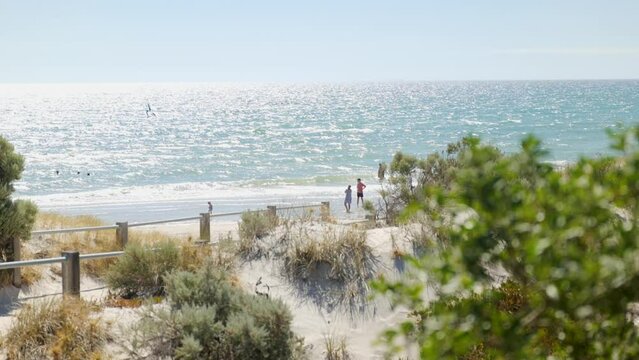 Man and Woman watch blue ocean in distance with
green bush in foreground Grange Beach South Australia