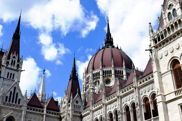 Obraz premium the cupola of the Hungarian Parliament in Neo-Gothic style . closeup perspective view from low angle. Famous and popular landmark and tourist attraction in Budapest. arched stone windows. blue sky