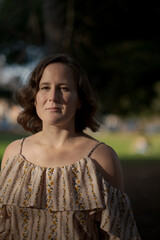 A person wearing an open-shoulder blouse expresses themselves outdoors in a park setting.