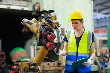 caucasian female engineering worker wearing safety hardhat helmet inspecting auto robot lathe machine to drill components. Metal lathe industrial manufacturing factory