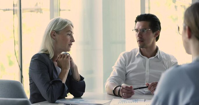 Skilled middle-aged businesswoman, marketing expert, consulting, explain strategy discuss business plan details to team during group meeting in boardroom, engaged in teamwork, work on project together