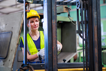 Caucasian female warehouse worker driving forklift truck at factory warehouse.