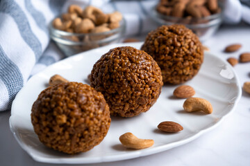 Energy bar nut balls cookie on white plate with almond and cashew. Recipe of simple homemade cookie with nuts full of protein and fats. Ketogenic diet or paleo diet dessert.