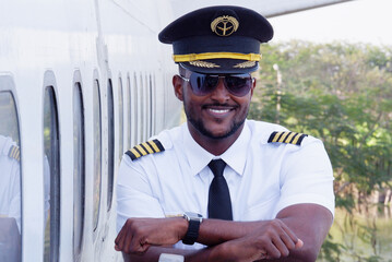 Young pilot standing smiling next to the plane.