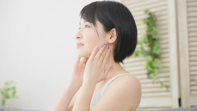 耳下腺のセルフマッサージをする若い女性　美容イメージ	