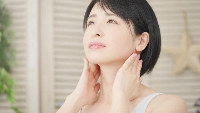 耳下腺のセルフマッサージをする若い女性　美容イメージ	