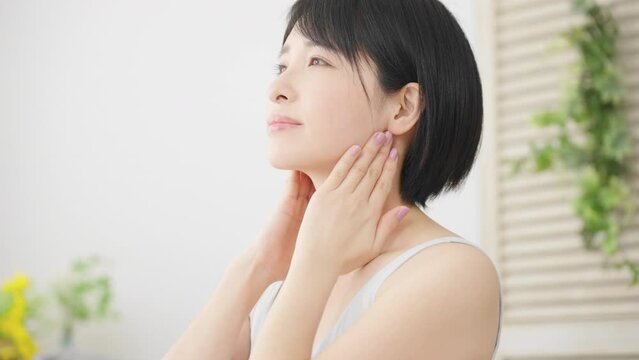 耳下腺のセルフマッサージをする若い女性　美容イメージ	