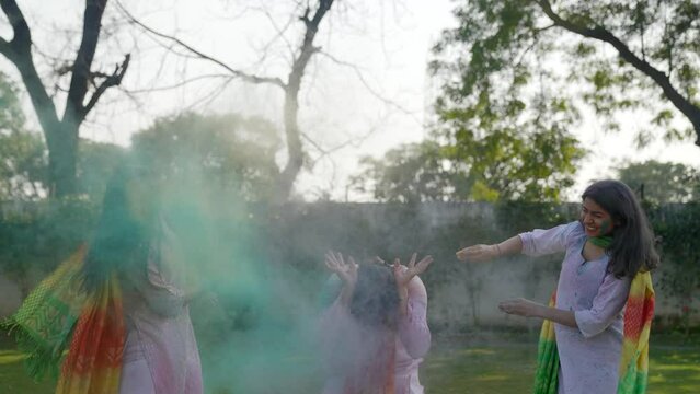 Indian girls throwing Holi colors on a boy