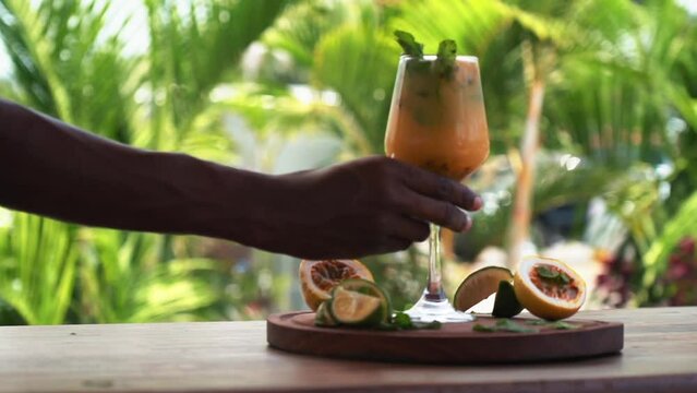 African bartender serving out passion fruit mojito in tropical background