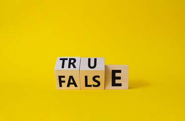 True vs False symbol. Wooden cubes with words False and True. Beautiful yellow background. Business and True vs False concept. Copy space.