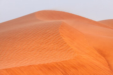 Close up of the ridge of desert dunes, with sand drifting in the wind