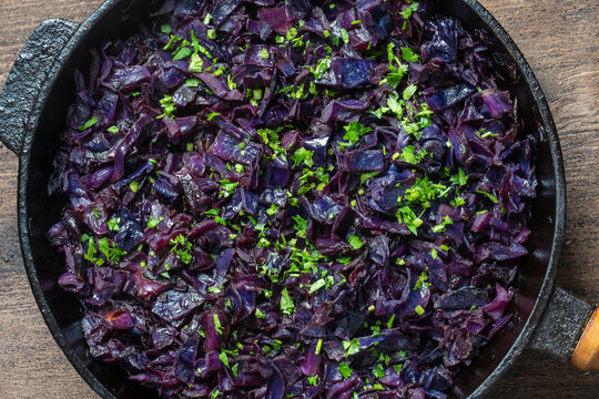 Red cabbage are pan-fried until lightly charred, then braised in mulled wine. Background of fry blue cabbage in a section, macro. Closeup, top view. Texture and pattern of purple cabbage