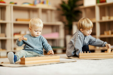 Children at kindergarten paying with wooden montessori toys and learning by playing.