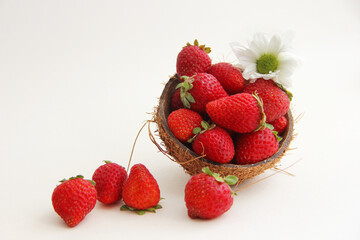 Strawberries in coconut peel. Juicy, red strawberries in a coconut plate on a white background