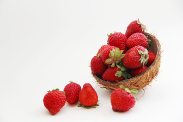Strawberries in coconut peel. Juicy, red strawberries in a coconut plate on a white background
