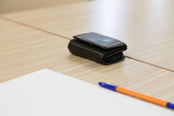 A pen with paper and wallet on wood table.