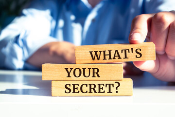 Closeup on businessman holding a wooden block with "What's your secret?"