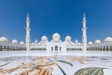 Symmetrical view of the main courtyard of the Sheik Zayed grand mosque in Abu Dhabi with the prayer hall flanked by minaret at the far end