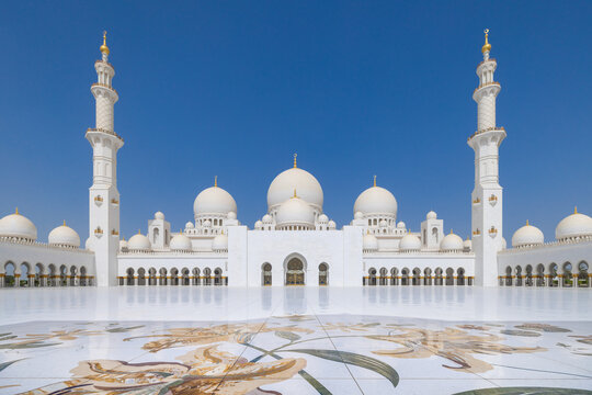 Symmetrical view of the main courtyard of the Sheik Zayed grand mosque in Abu Dhabi with the prayer hall flanked by minaret at the far end