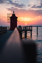 Fototapeta na wymiar Steg mit Leuchtturm zum Sonnenaufgang am Meer.