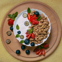 Granola with yogurt - a healthy breakfast of oatmeal close-up with strawberries and blueberries. Top view