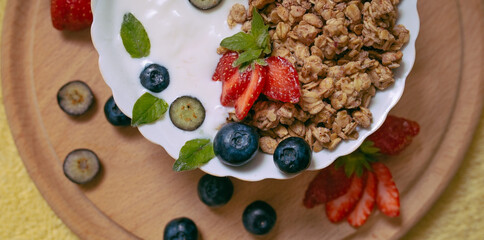 Granola - healthy breakfast of yogurt with oatmeal, nuts, berries and honey close-up with strawberries and blueberries