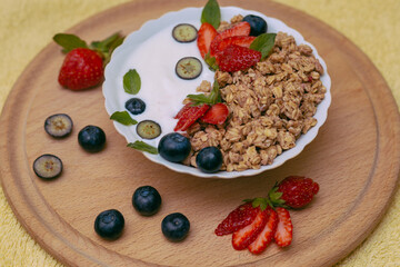 Granola with yogurt - a healthy breakfast of oatmeal close-up with strawberries and blueberries. 