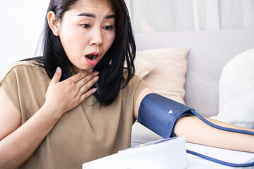 Asian woman self-checking her health and shocked with high blood pressure result