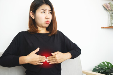 Asian woman suffering from Epigastric pain caused by acid indigestion, GERD or too much gas in the stomach