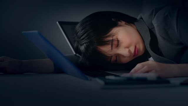 オフィスで寝落ちする若い女性　残業イメージ	
