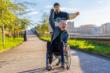 Disabled person in wheelchair with friend overjoyed, smiling, enjoying with arms up, vistoria, enjoying life