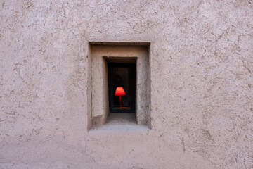 Red lamp light on a window of a kasbah with mud walls