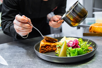 chef hand preparing Meat Pie with mashed potato and salad on restaurant kitchen