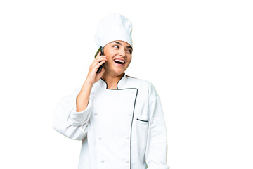 Young woman Chef over isolated chroma key background keeping a conversation with the mobile phone