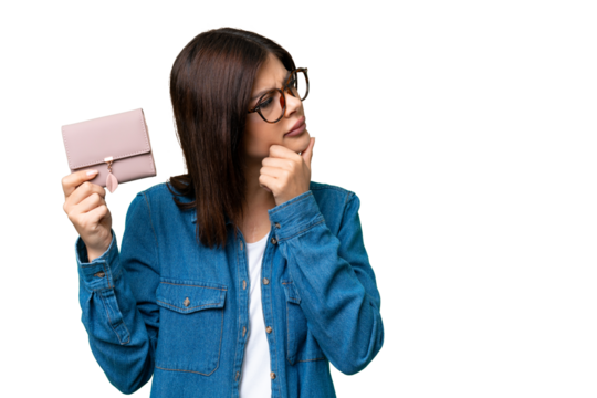 Young Russian woman holding a wallet over isolated chroma key background thinking an idea and looking side