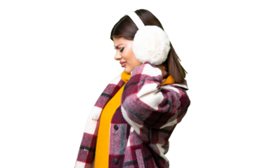 Young Russian woman wearing winter muffs over isolated chroma key background with neckache