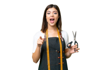 Seamstress woman over isolated chroma key background surprised and pointing front