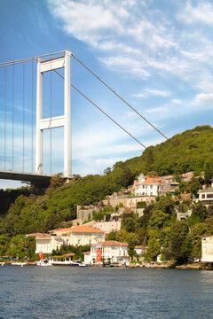 View from the sea of the Asian side of Bosphorus strait, Istanbul, Turkey, with traditional waterfront houses, under Bosphorus bridge, and green hill with dense trees, in a summer day