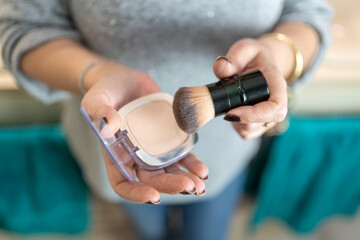 Close-up of older woman's hands handling makeup items.