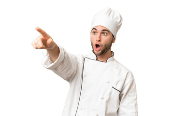 Young handsome chef man over isolated background pointing away