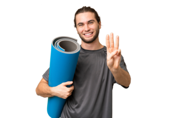 Young sport man going to yoga classes while holding a mat over isolated background happy and counting three with fingers