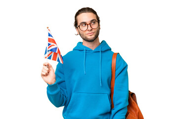 Young handsome man holding an United Kingdom flag over isolated background looking to the side