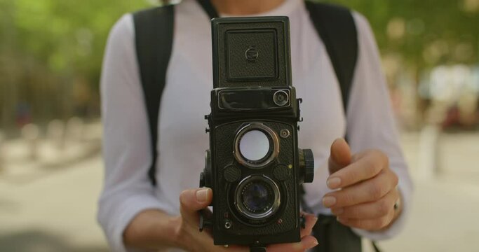 Young professional female photographer open viewfinder latch on old analog medium format camera, spin exposure and manual focusing ring. Film analog photography